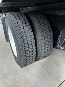 Dual rear truck wheels and dual-tire setup under Freightliner M2-106 chassis showing tread pattern and wheel rims.