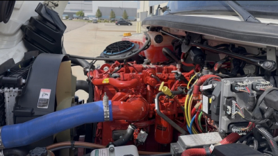 Freightliner M2-106 engine bay showing red turbo diesel engine with blue intercooler hose and various wiring harnesses