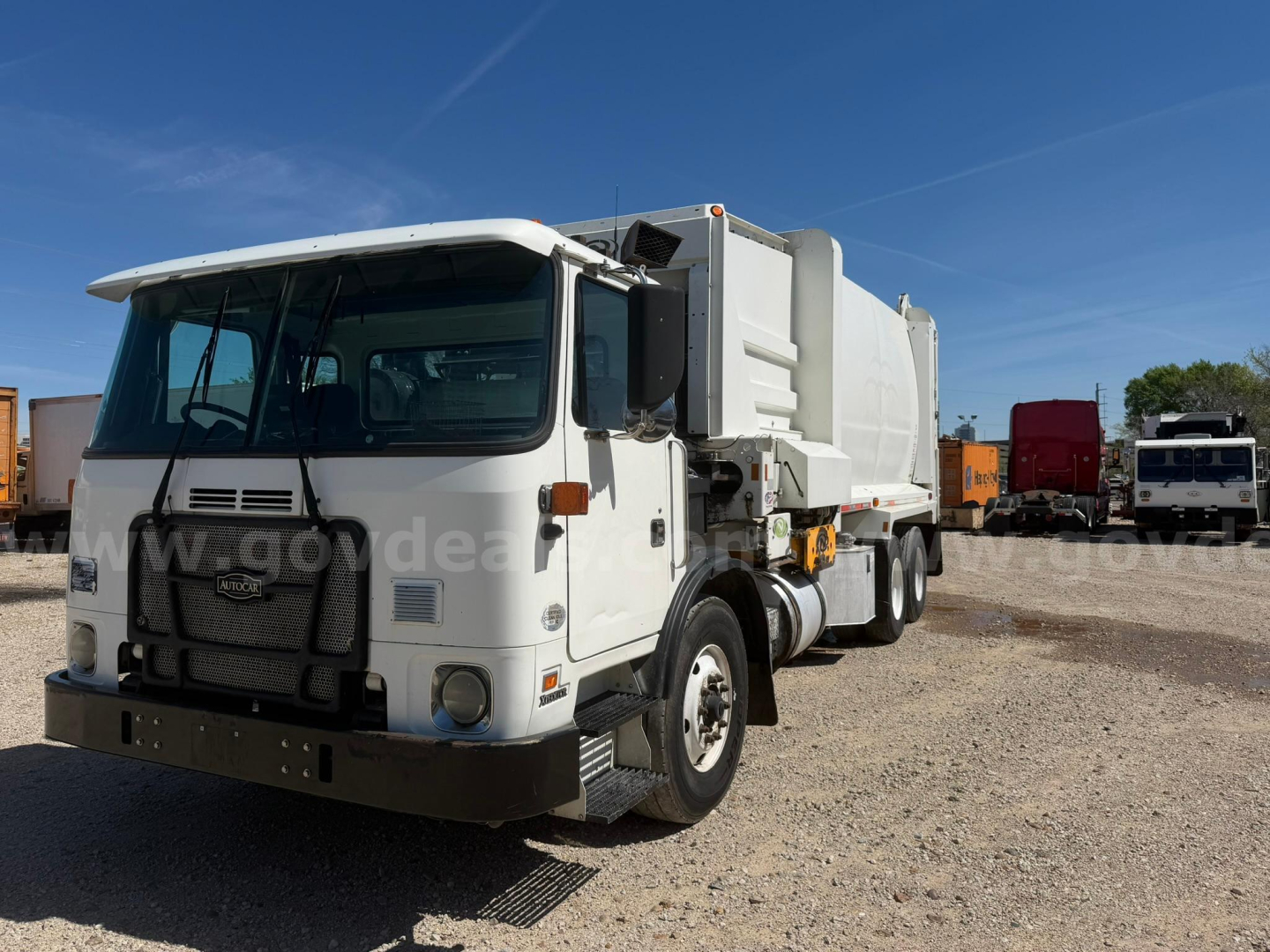Autocar Xpeditor dump truck front-side view showing cab and dump body in a yard.