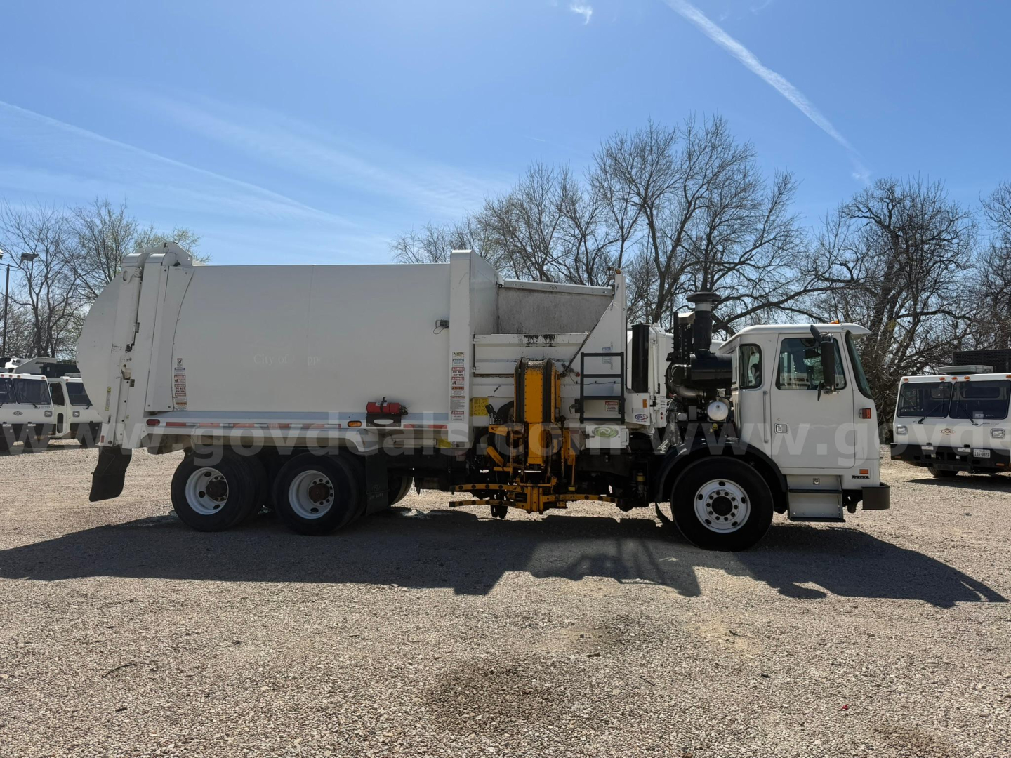 Autocar Xpeditor truck with garbage body showing rear-compartment and service controls mounted near cab; side view includes hydraulic machinery and cables.