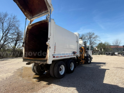 Autocar XPeditor dump truck with open bed, side view showing large white dump body and rear gate, dual rear axles, front cab visible