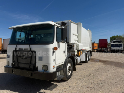 Autocar Xpeditor dump truck front-side view showing cab and dump body in a yard.