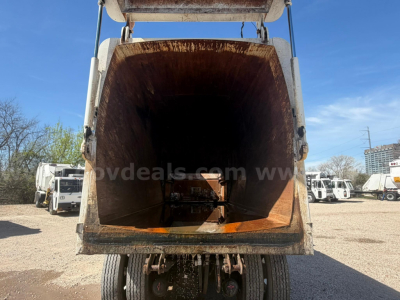 Autocar XPeditor truck hopper seen from rear with open steel intake showing rusted interior and hydraulic arms on sides.