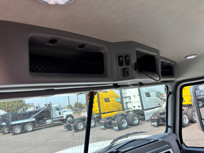 Cab interior of a 2027 Mack PI64T showing overhead storage compartments and control panel in view from driver's seat.