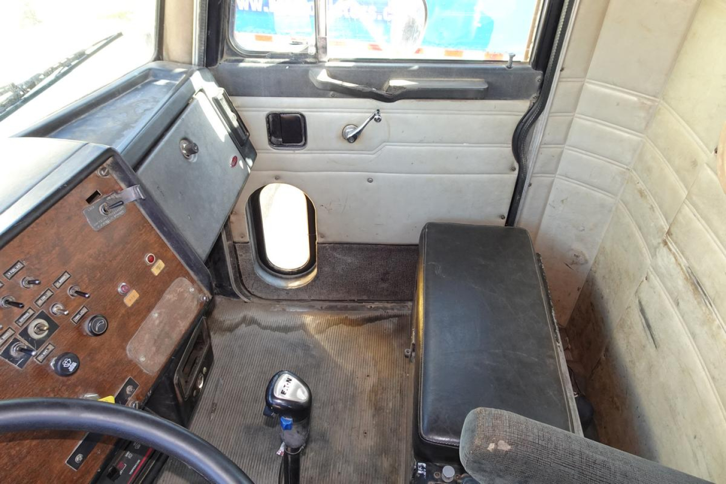 Cab interior of a 1988 Peterbilt 357 dump truck showing steering wheel, dashboard with switches, gear shifter, passenger seat and door panel.