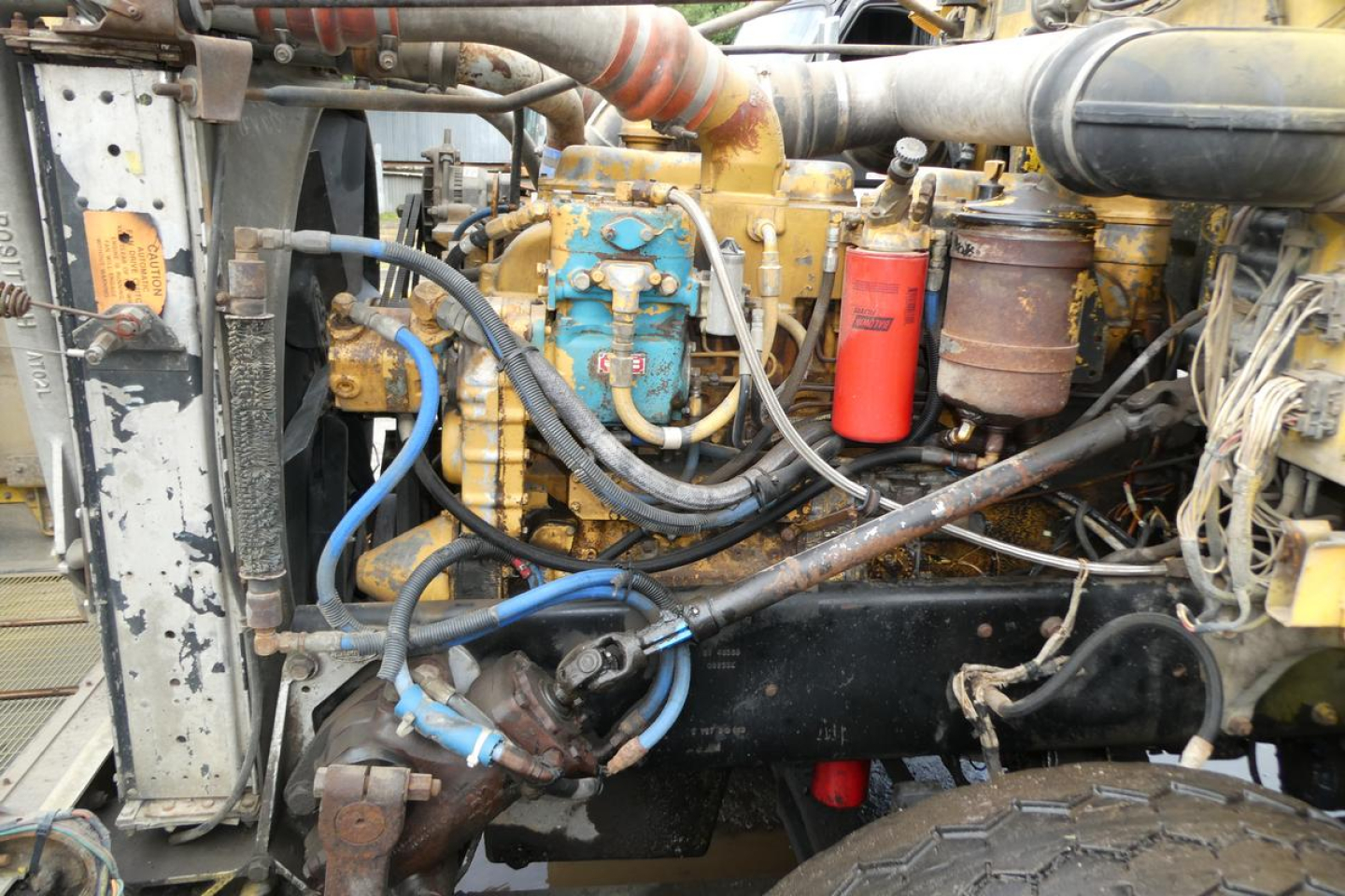 Tractor-engine bay of a 1988 Peterbilt 357 dump truck showing diesel engine with blue pump, red filter, hoses, and metallic components.