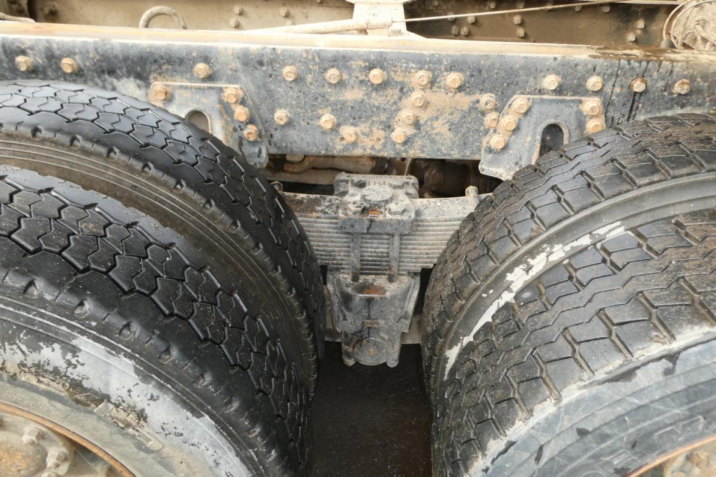 Rear view showing dual rear axles with mud and grime, Peterbilt truck chassis center with suspension and differential visible.