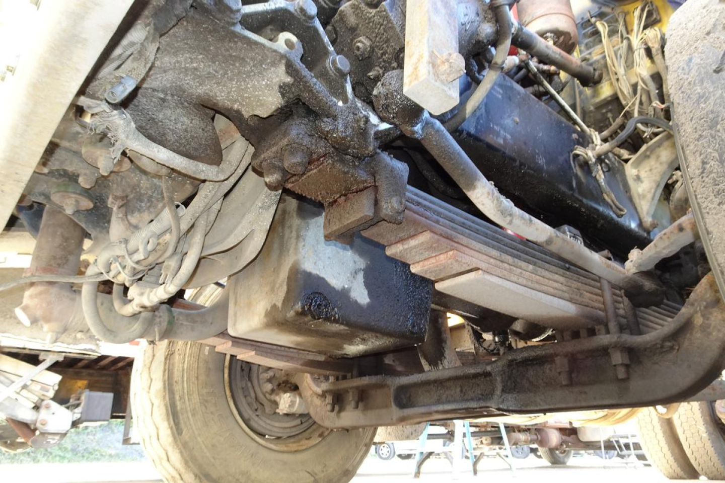 Underbelly of a 1988 Peterbilt 357 dump truck showing frame, suspension, fuel tank, and exhaust piping with visible hoses and wiring.