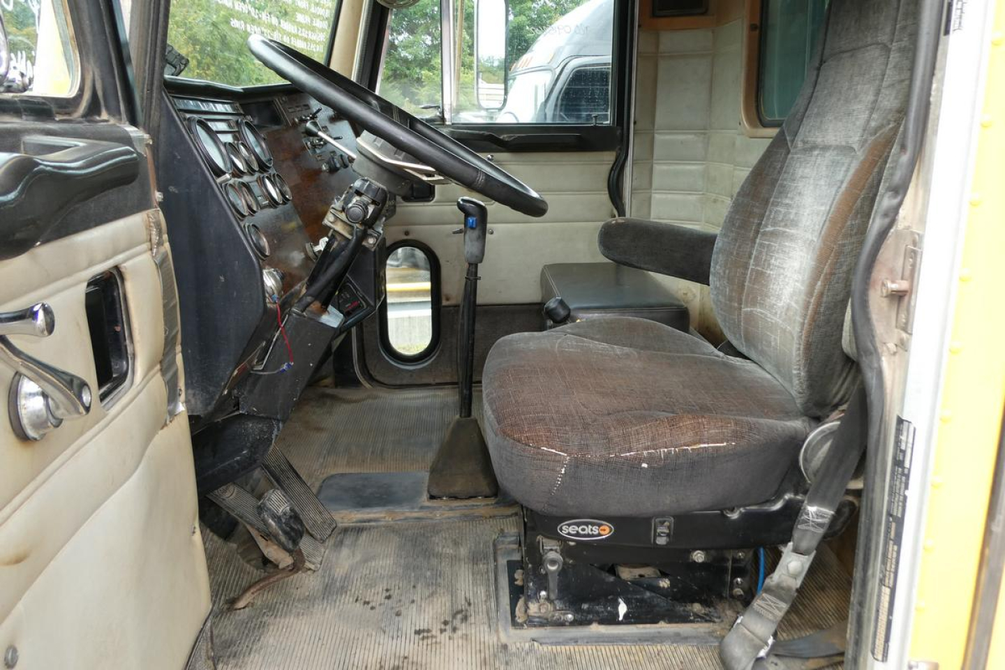 Peterbilt truck cabin interior showing steering wheel dash and worn driver seat