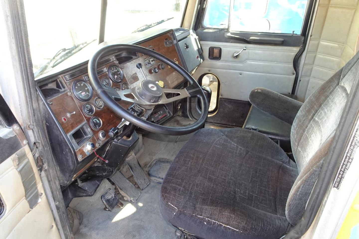 Peterbilt 357 dump truck dashboard and driver’s seat interior with brown wood-grain panels and analog gauges.