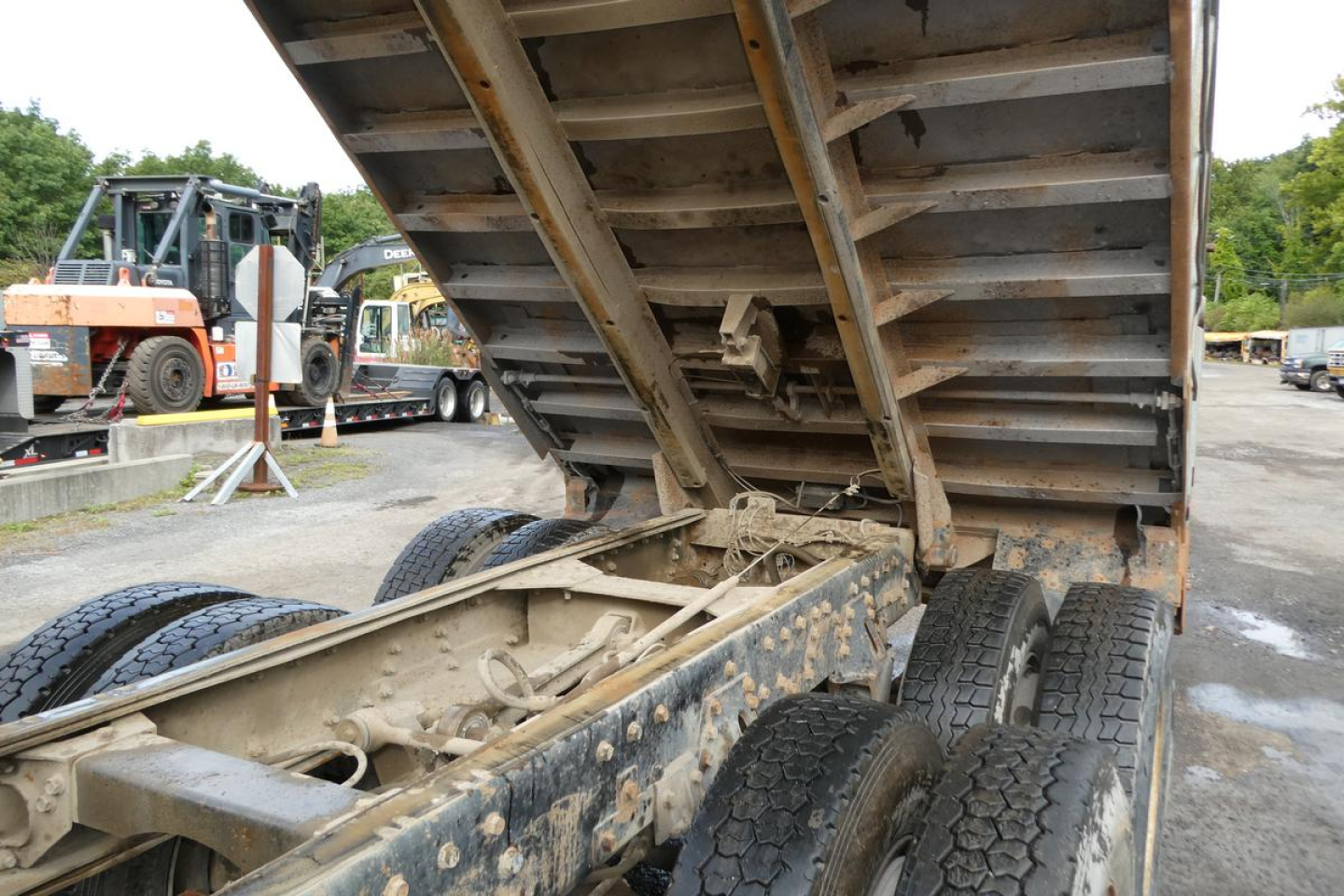 Peterbilt dump truck chassis and raised dump bed showing dual rear axles and undercarriage with hydraulic linkage and rust-resistance soiled components