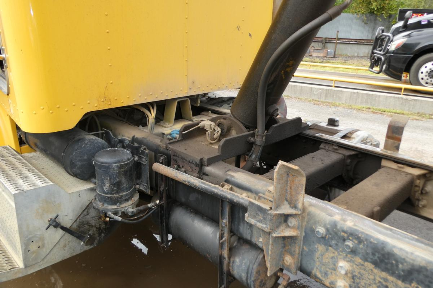 Peterbilt 357 dump truck chassis and hitch area with yellow body and black frame, showing hitch, piping, and oil reservoir