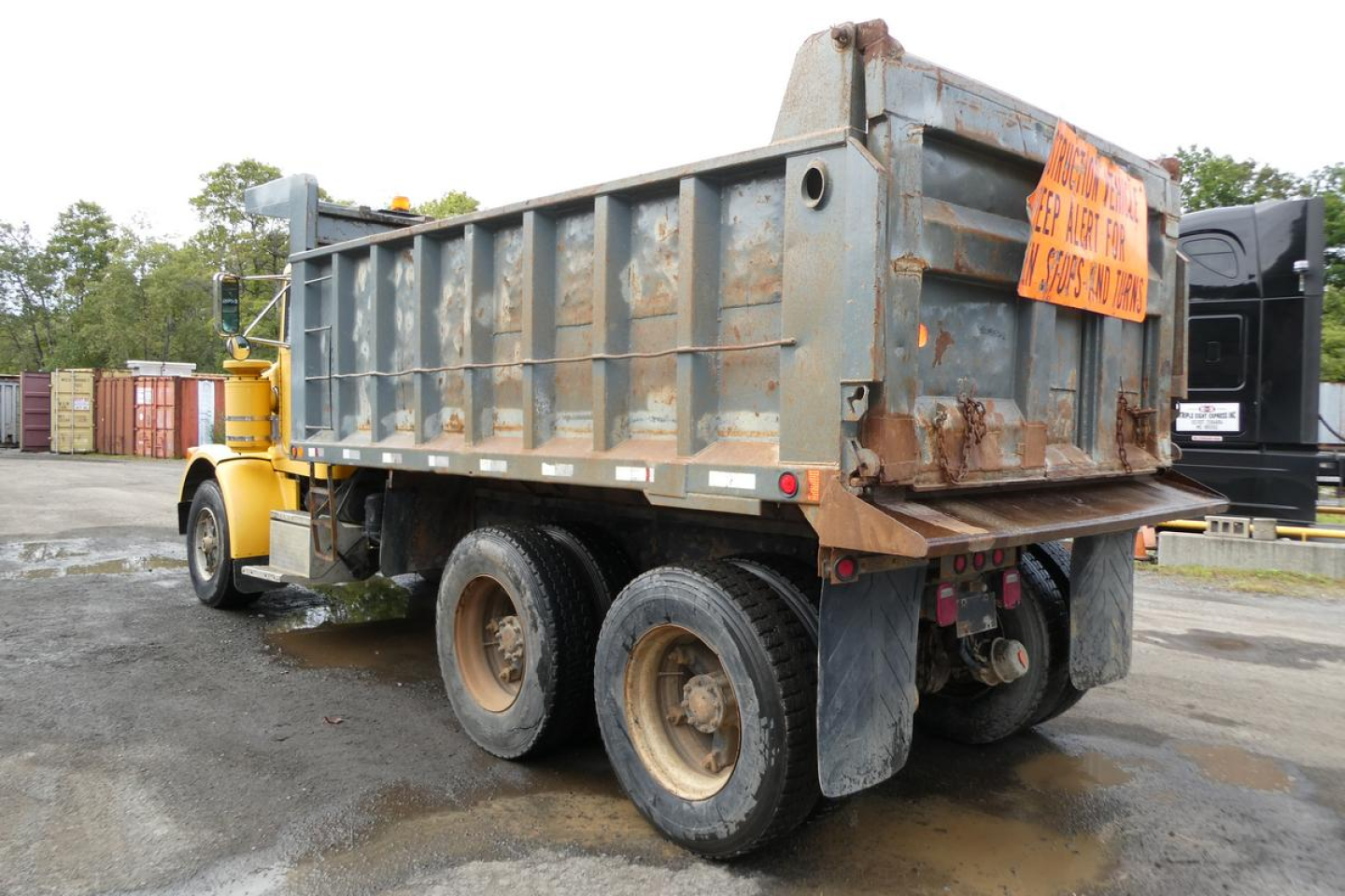 Dump truck showing rear of a Peterbilt 357 dump bed with rust and orange warning sign