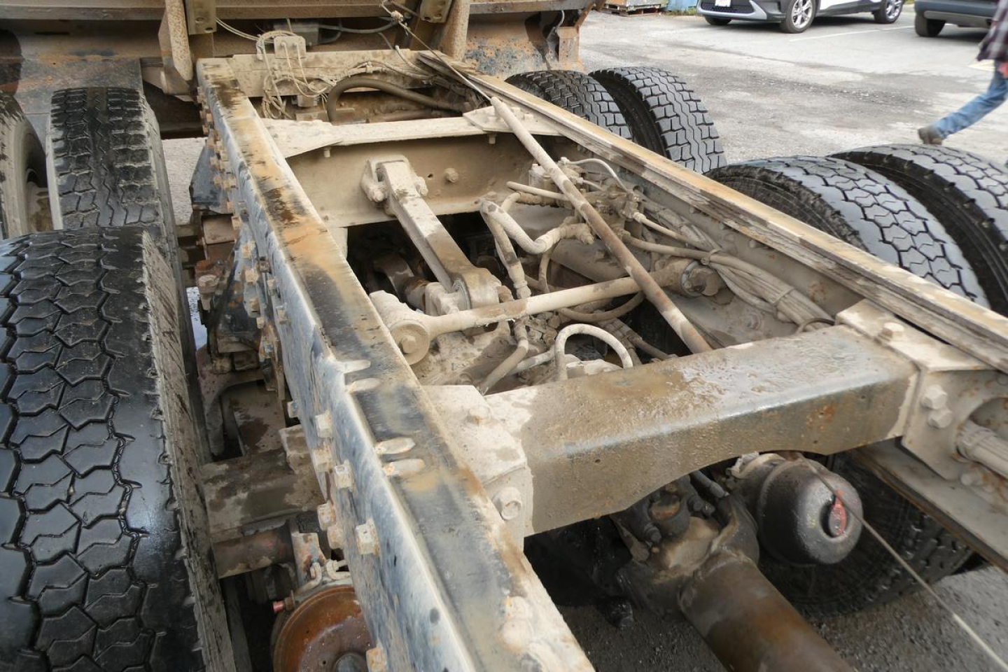 Suspension and chassis of a Peterbilt truck trailer frame showing leaf springs, axles, and linkage undercarriage with dirt and grime.