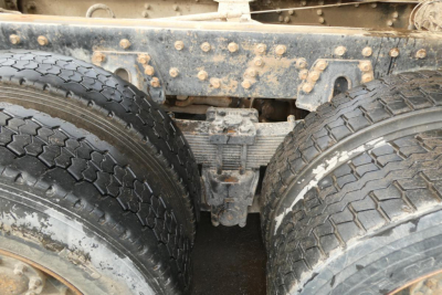 Rear view showing dual rear axles with mud and grime, Peterbilt truck chassis center with suspension and differential visible.