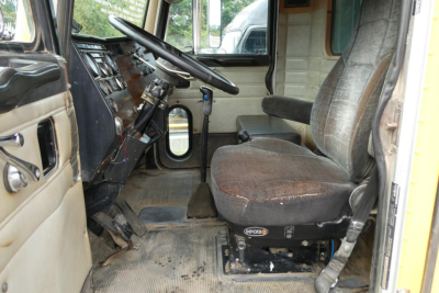 Peterbilt truck cabin interior showing steering wheel dash and worn driver seat