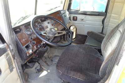 Peterbilt 357 dump truck dashboard and driver’s seat interior with brown wood-grain panels and analog gauges.