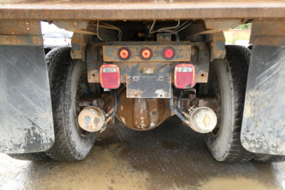 Rear view of Peterbilt truck showing hitch, taillights, and dual rear wheels with mud flaps and rust on frame.