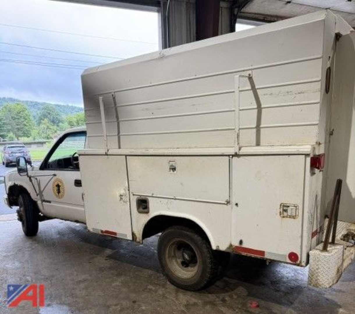 White service body pickup truck, side view showing utility box with compartments and rear wheel, Chevrolet badge not visible.