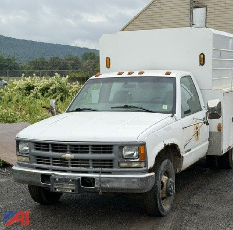 Chevrolet truck from front-left view showing utility box on chassis, 1998 C/K 3500 series, with dual headlights and grille, front bumper, and wheel missing hubcap