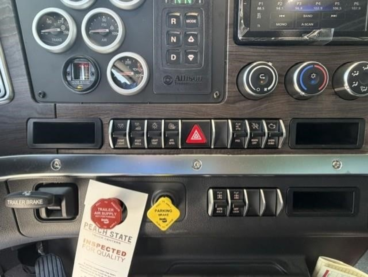 Truck dashboard interior showing gauges, control switches, hazard button, and climate controls in cabin of a Western Star 47X cab.