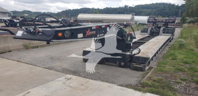 Lowboy trailer showing XL Specialized XL110HDGS15 with hydraulic gooseneck and deck, in-service; visible components include hydraulic hoses, control box, and steel deck.