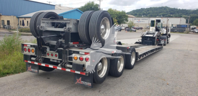 Trailer rear view showing lowboy trailer deck with dual axle and three axles, spare tires mounted on rear, and landing gear; XL Specialized XL110Hdgs15 in yard.
