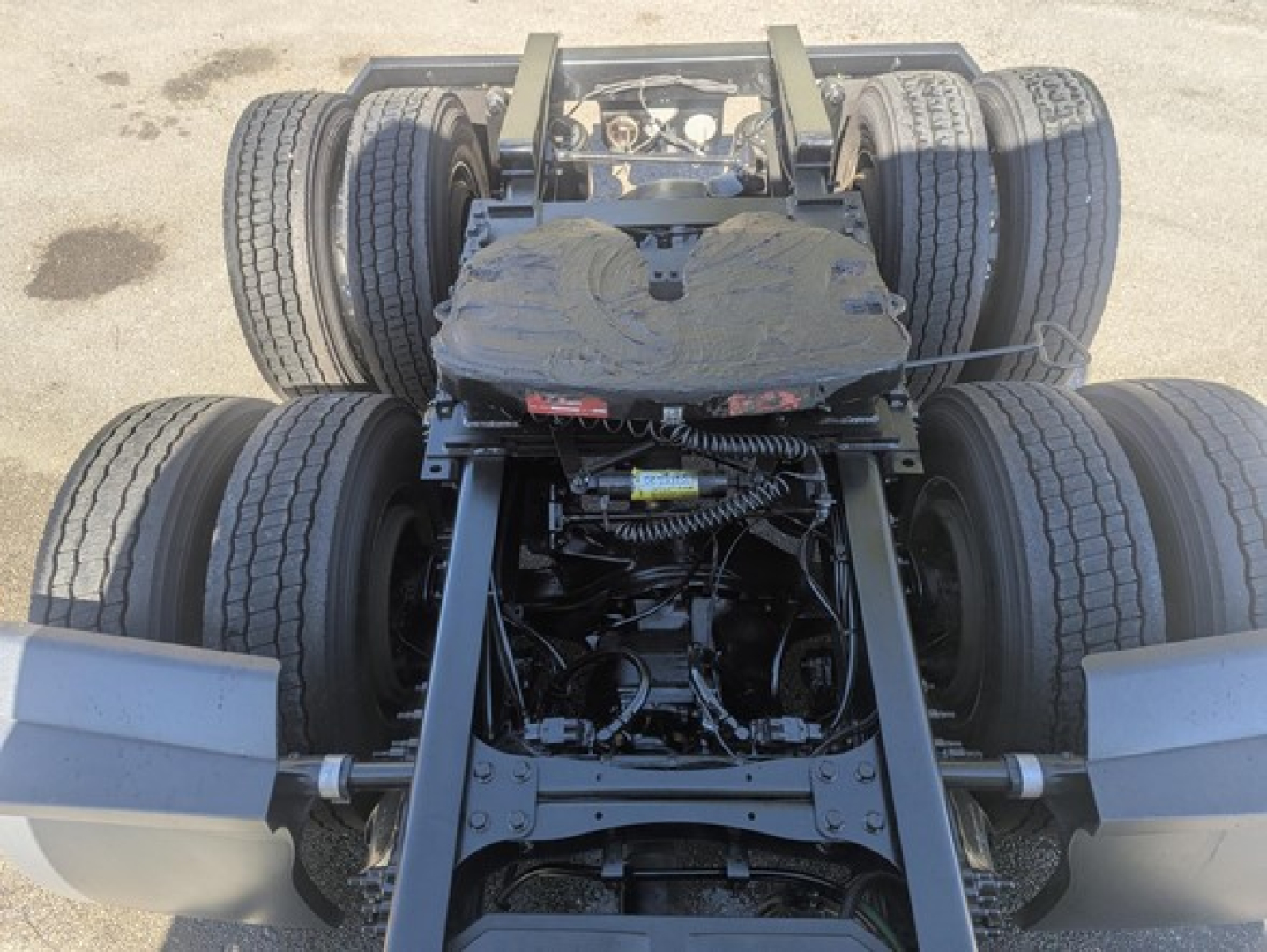 Truck chassis and drive axles of a Freightliner Cascadia 126 seen from rear, showing dual rear axles, suspension, and exposed drivetrain components.