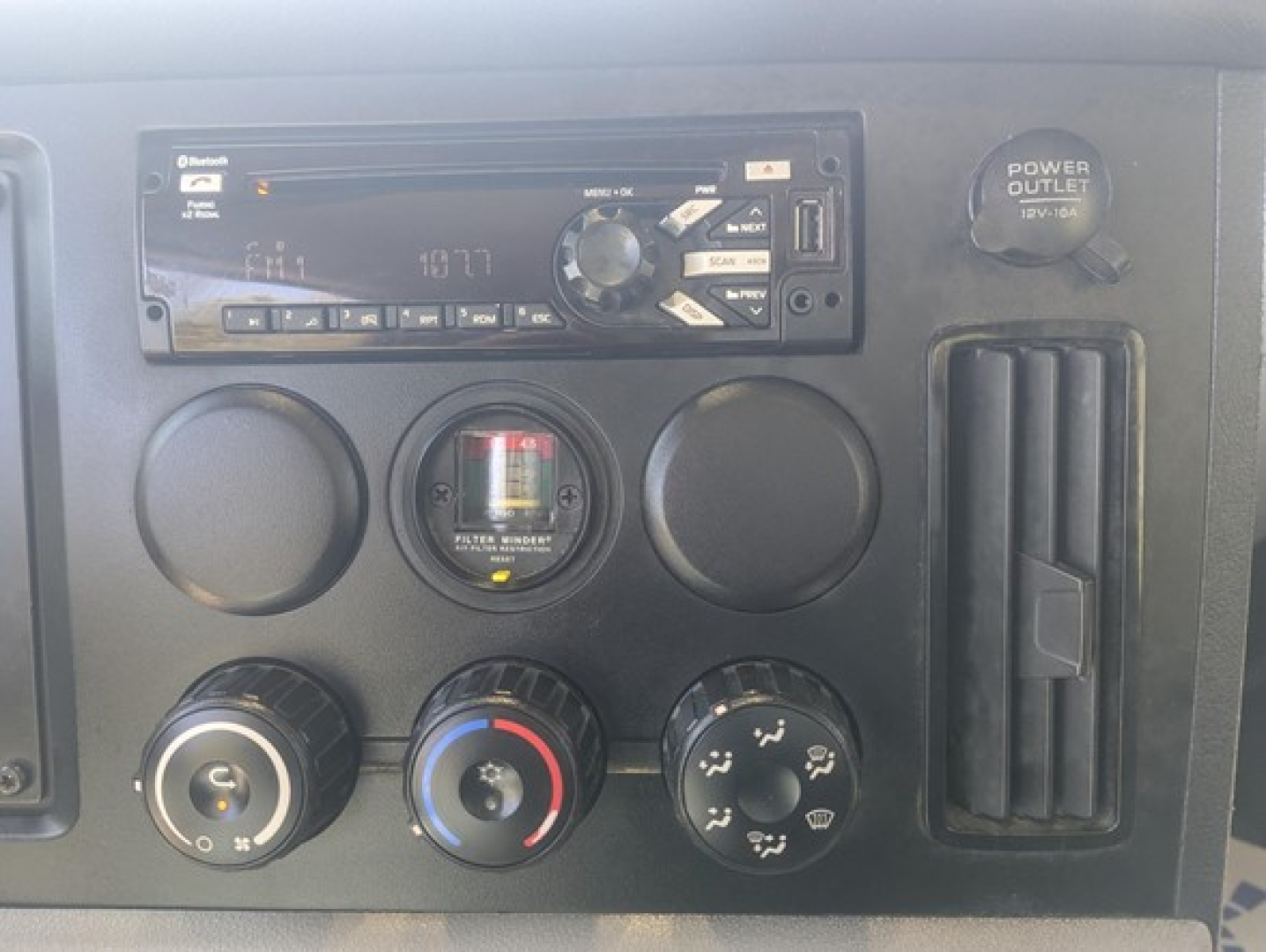 Truck dashboard panel showing a stereo unit, circular vents, a gauge cluster, and climate controls. Visible text includes a Pioneer or similar head unit and various knobs.