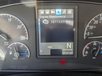Cab dashboard display showing Engine Maintenance screen and 10773:21 hrs, with N gear indicator, speedometer, and fuel gauge in Freightliner Cascadia 126 cab.