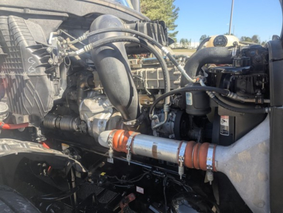 Engine bay of a 2021 Freightliner Cascadia 126 day cab showing turbo, intercooler piping, hoses, and detector with orange coolant hose clamp.