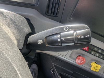 Truck interior steering column shifter with gear indicator N R M and buttons, plus red and yellow controls on dash.