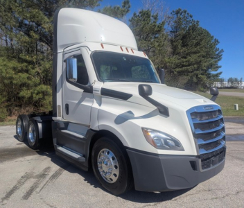 Truck cab in spotlight showing Freightliner Cascadia 126 sleeper with large blue grille and side mirrors.