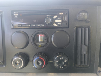 Truck dashboard panel showing a stereo unit, circular vents, a gauge cluster, and climate controls. Visible text includes a Pioneer or similar head unit and various knobs.