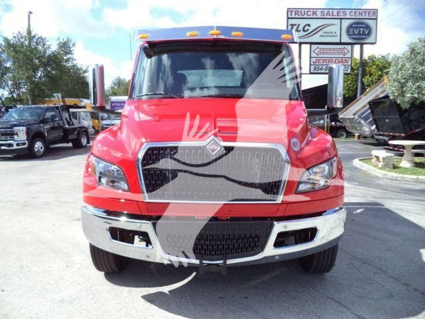 Front view of a red 2027 International MV truck showing grille, headlights, bumper, and dealership lot in background.