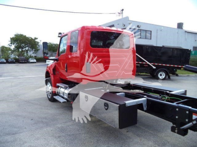 Truck chassis and cab of a red 2027 International MV rollback truck with extended cab and side exhaust, seen from rear-left side.