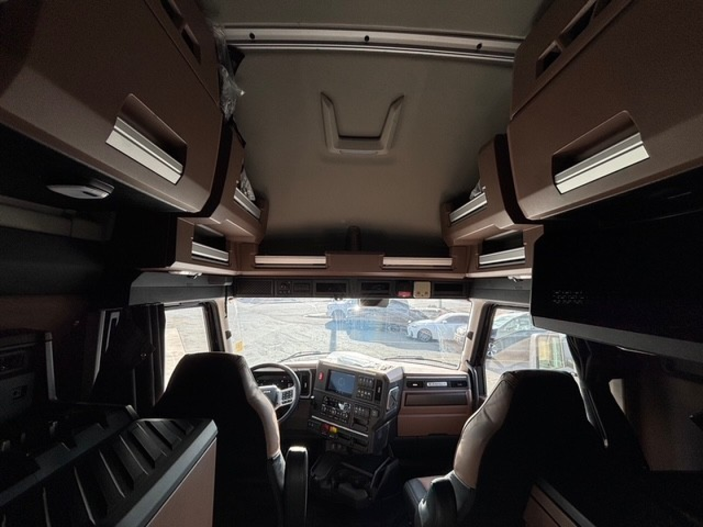 Interior view of a Mack PR64T76H sleeper cab truck showing overhead cabinets, dashboard, and seating from the sleeper area.