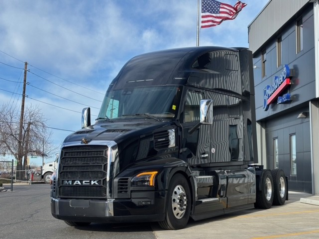 Truck cab of a black 2026 Mack PR64T76H sleeper tractor showing front grille with Mack emblem and chrome bumper.