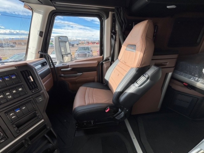 Cab interior of a 2026 Mack PR64T76H truck showing driver seat with tan and black upholstery and dashboard controls.