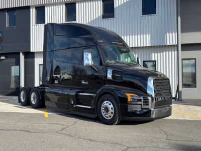 2026 Mack PR64T76H conventional sleeper truck in black, front three-quarter view, parked outside a modern building.