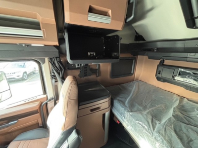 Interior cab view of a new 2026 Mack PR64T76H sleeper truck showing bunk area, overhead storage, and dash area with protective plastic on bunk.