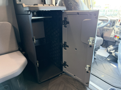 Cabinet/locker inside a 2027 Mack PR64T76H sleeper truck showing open storage cabinet with multiple shelves and a light gray door.