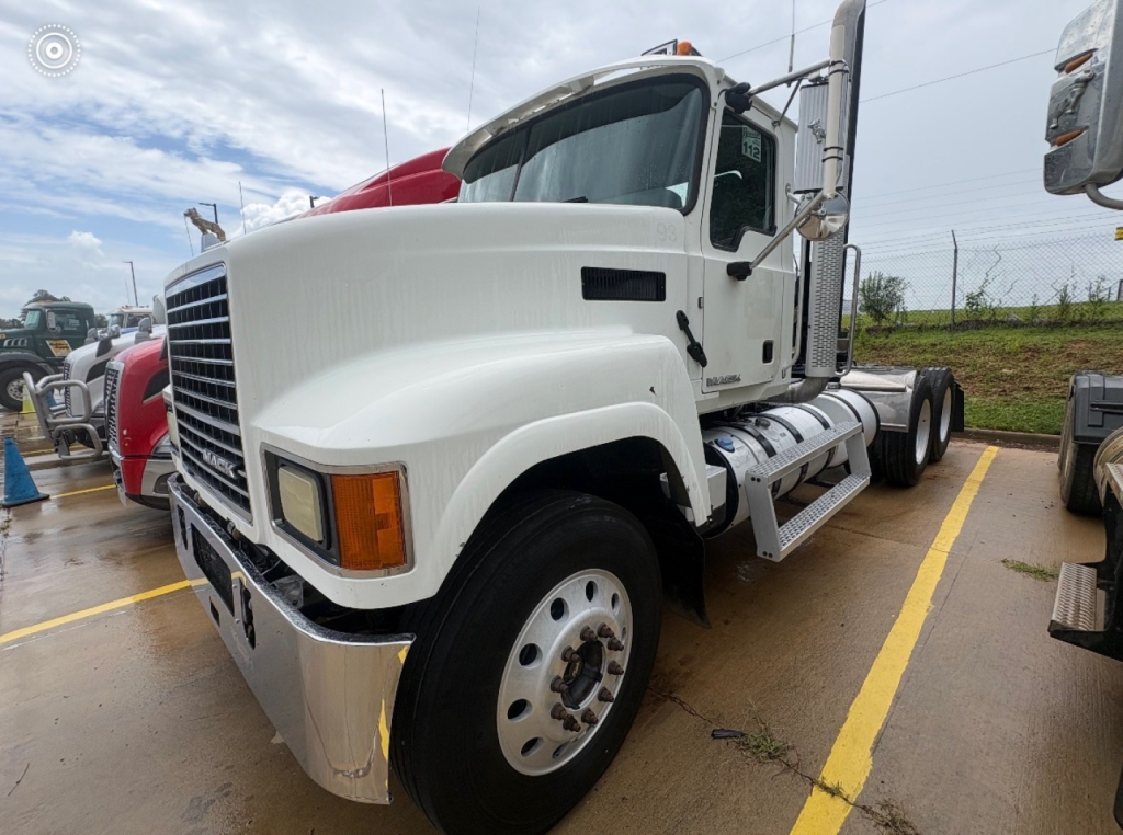 Truck cab showing front and side view of a white 2016 Mack CHU613 daycab with large grille, side steps, and dual rear axles.