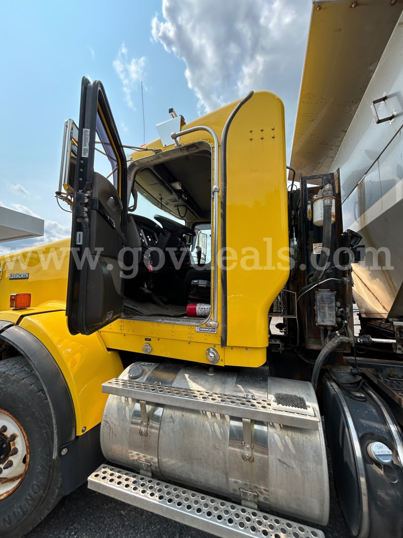 Kenworth T800 truck cab door open showing interior and steps; yellow body with aluminum fuel tank and side plow apparatus nearby.