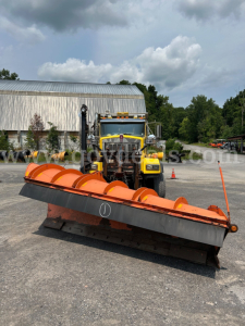 Front view of a yellow Kenworth T800 plow truck with an orange snow plow attachment, parked on a lot.