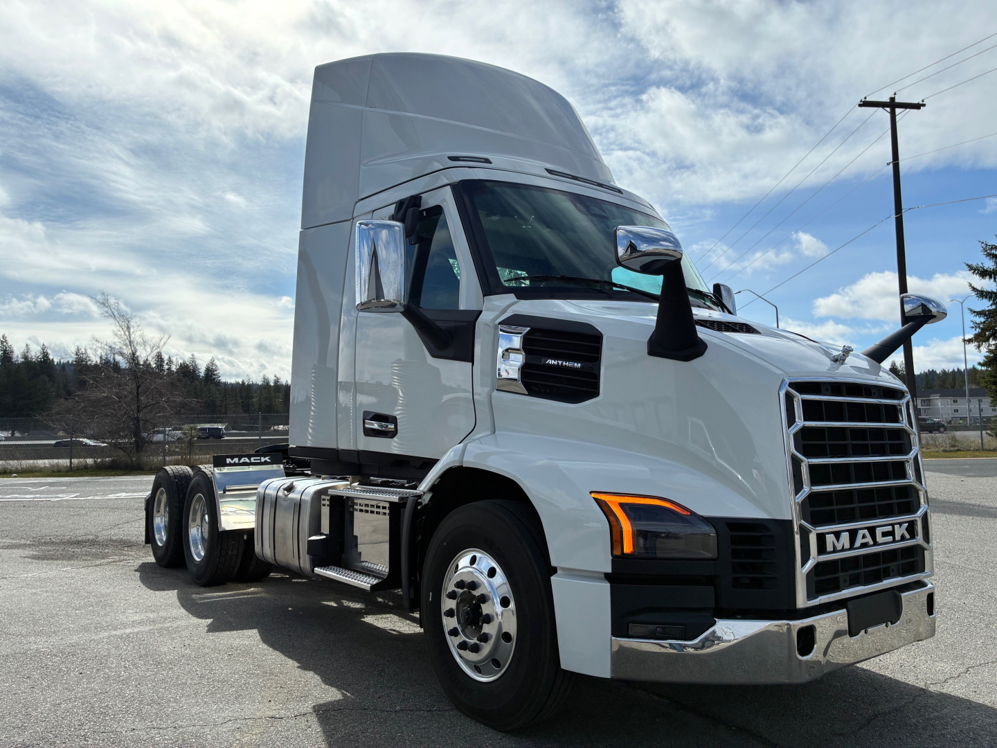 Truck side view showing 2027 Mack AN64T conventional daycab with sleeper hood, large grille, chrome bumper, stacked dual rear wheels, and white paint.