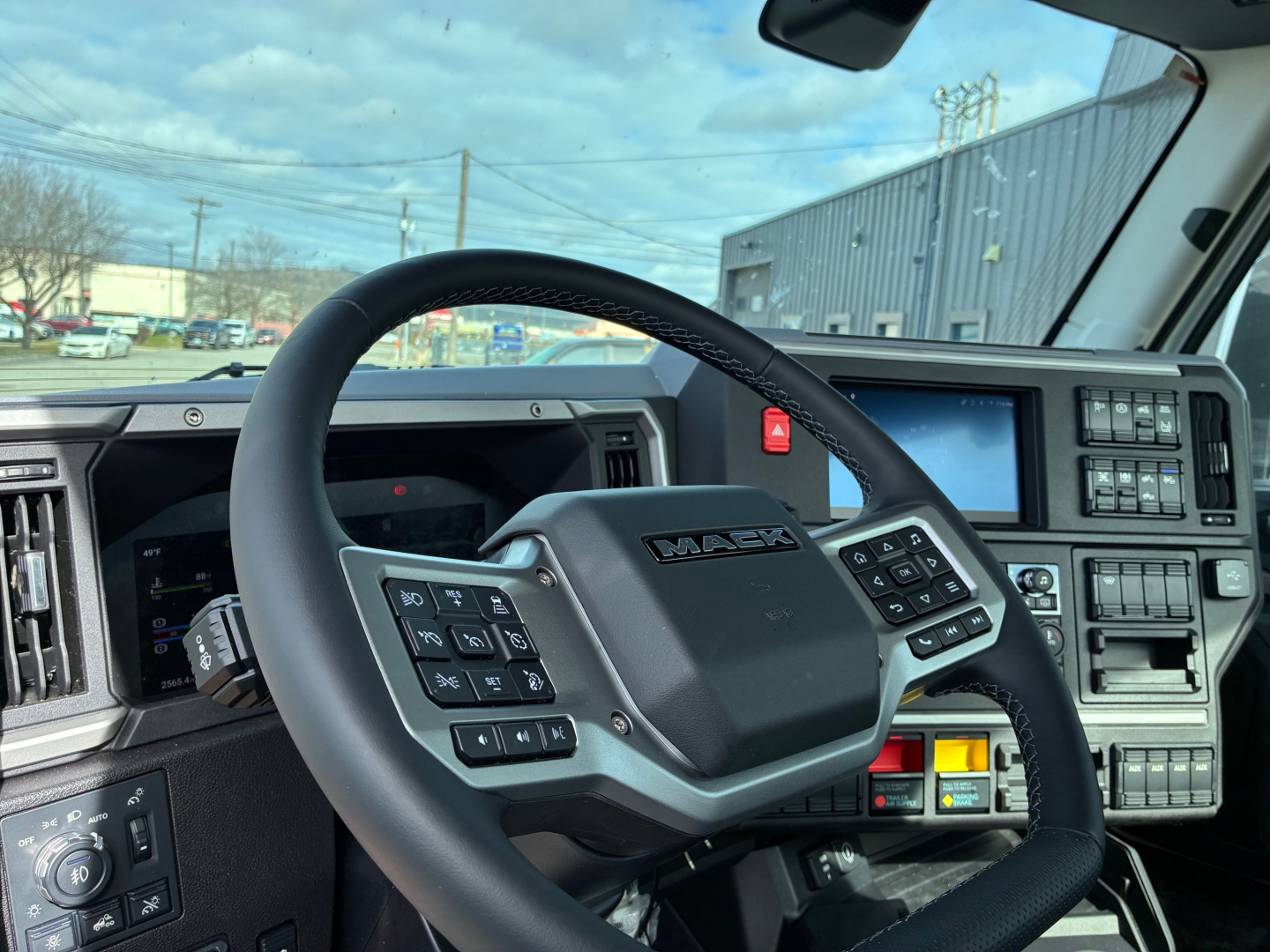 Mack AN64T truck cab interior showing steering wheel with integrated controls and dashboard display.