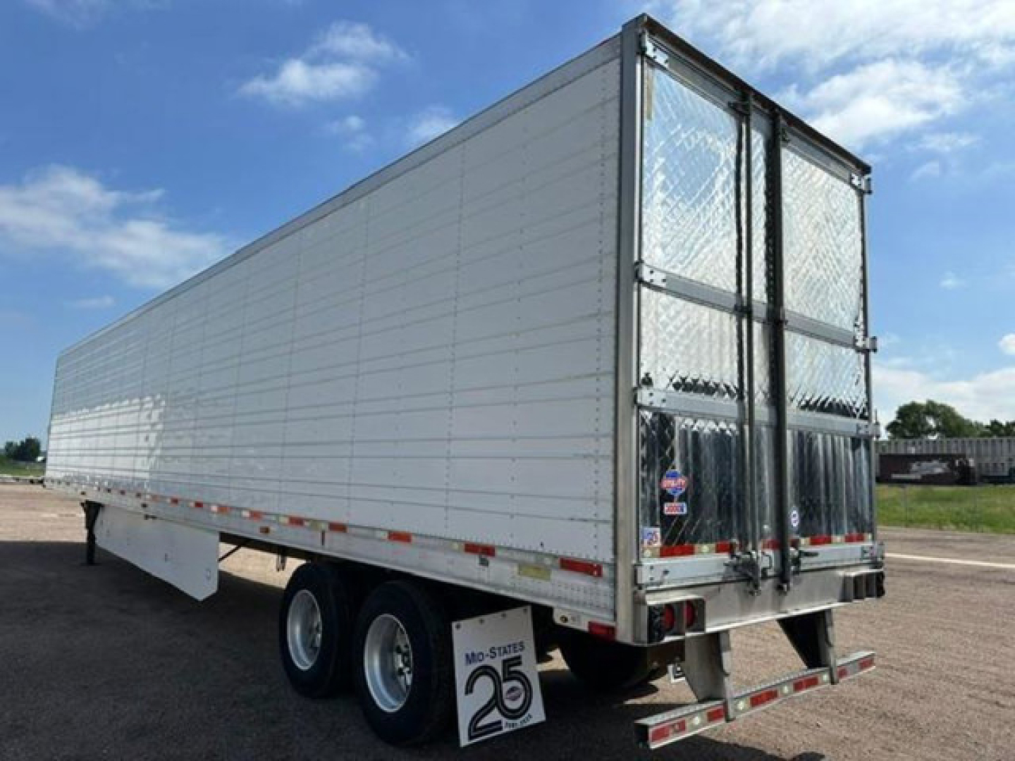 Refrigerated trailer showing rear doors with diamond plate and metal framework. Side of trailer plain white with riveted panels.