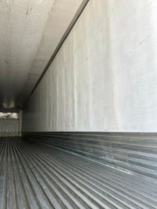 Interior of a refrigerated trailer cargo space showing ribbed floor and smooth side walls.