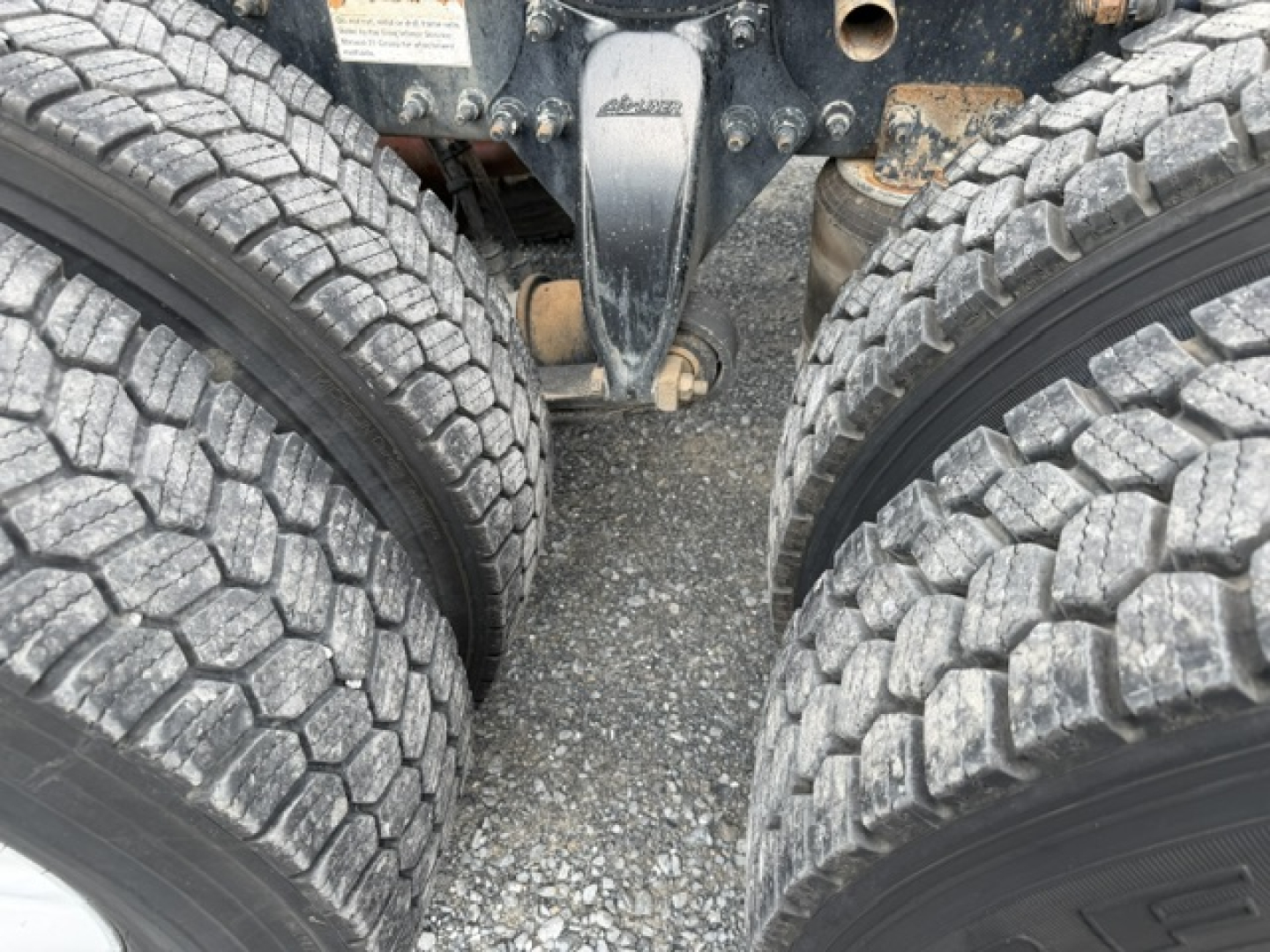 Freightliner Cascadia (CA125DC) undercarriage showing dual rear axles and tire tread, with hitch and chassis components visible.